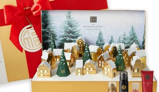 Otevřený zlatý adventní kalendář Rituals s vesničkou a ukázkou kosmetiky.