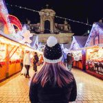 Dívka stojící mezi stánky na vánočních trzích ve francouzském Nancy.